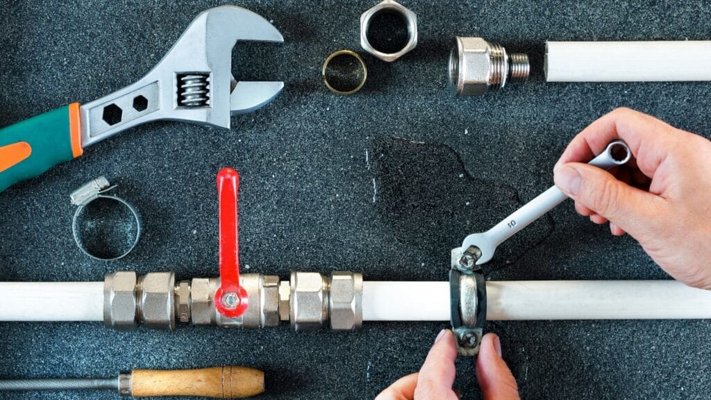 Plumber repairing a pipe valve with an adjustable wrench in Port Charlotte