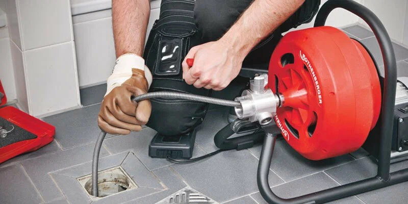 Plumber using a drain-cleaning machine in Port Charlotte