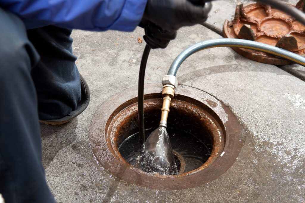 Plumber hydro jetting a sewer line through a manhole in Port Charlotte