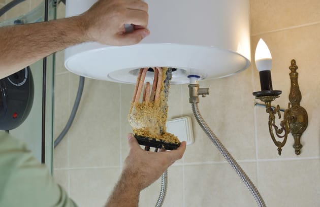 Technician removing mineral buildup from a water heater in Port Charlotte